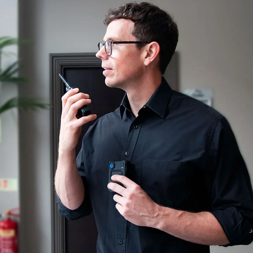 A security officer using a two-way radio and body-worn camera